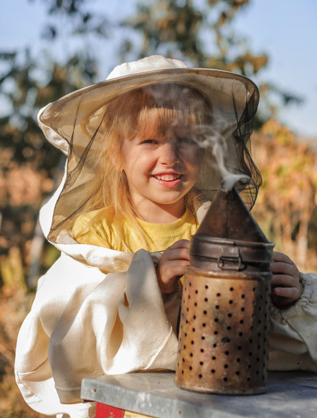 Mała dziewczynka pszczelarz wieje palacz dla pszczół - Zdjęcie, obraz