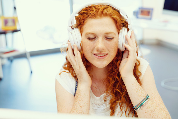 Young woman with headphones working in office - Photo, image