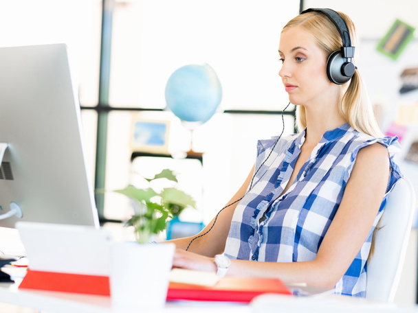 Young woman working in office with headphones - Foto, immagini