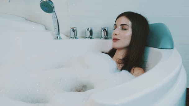 Chica acariciándose en la bañera llena de espuma. Disfruten. Satisfacción. Sonríe
 - Metraje, vídeo