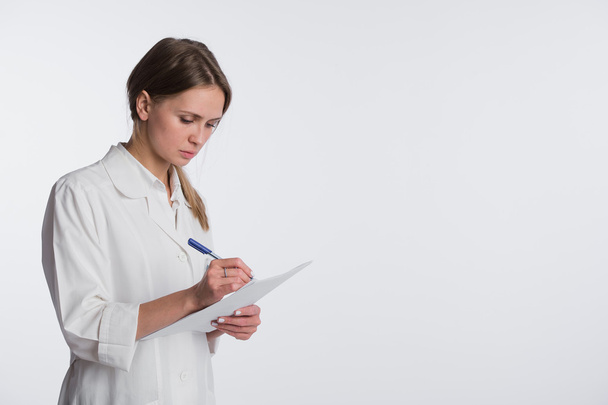 schöne Krankenschwester lächelnd und Notizen auf einem weißen isolierten Hintergrund - Foto, Bild
