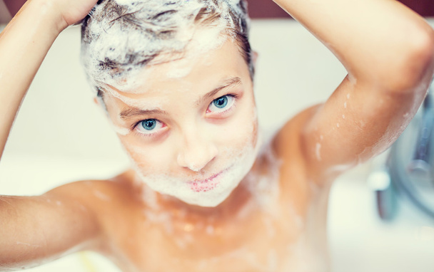 Cute young girl in shower washing hair and face with shampoo. girl with braces - Foto, afbeelding