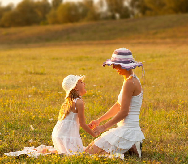 Mother and daughter having fun on the meadow on sunny summer day - 写真・画像
