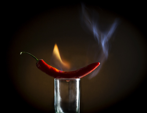 Peperoncino rosso piccante con fiamme sul bicchiere
 - Foto, immagini