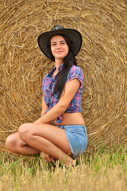 Una giovane cowgirl che sogna ad occhi aperti in un campo di fieno
 - Foto, immagini