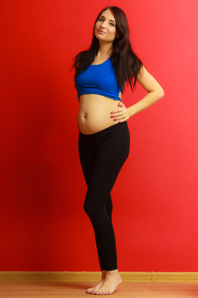 Long hair fit pregnant woman on red - Foto, immagini
