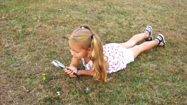 Een meisje kijkt door een vergrootglas - Video