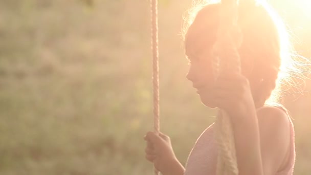 das Mädchen schüttelt sich auf einer Schaukel bei Sonnenuntergang - Filmmaterial, Video