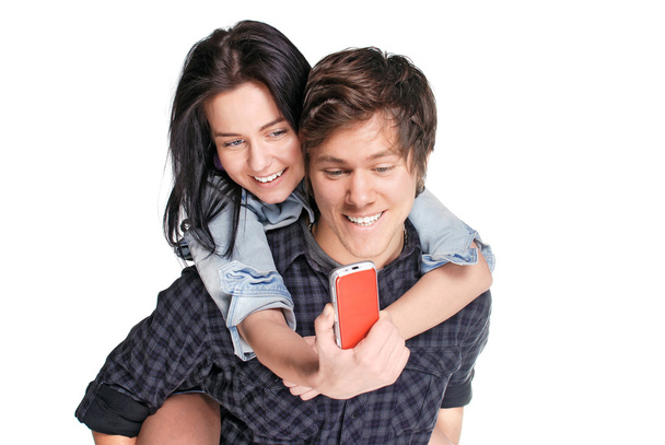 Souriant jeune homme piggyback sa jolie petite amie en regardant le téléphone
 - Photo, image