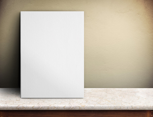 Blank White paper poster on marble table at yellow concrete wall - Foto, Bild