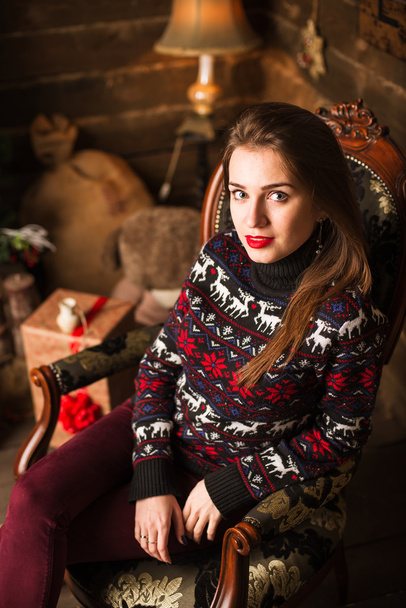 Young girl sitting next to Christmas tree and gifts - Фото, изображение