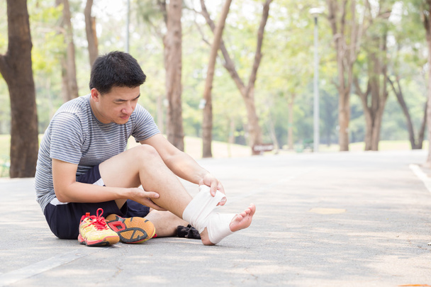 Sportverletzung. Mann mit Schmerzen im Knöchel und bandagiertem Fuß - Foto, Bild