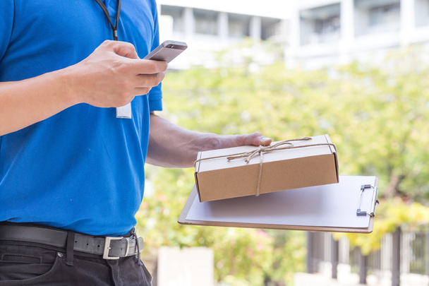 Zusteller hält Paketkasten in der Hand und telefoniert mit dem Kunden - Foto, Bild