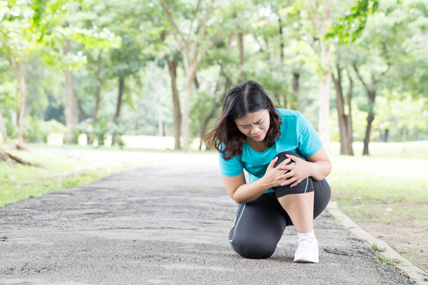 Aziatische jonge vrouw met kniepijn tijdens het sporten - Foto, afbeelding