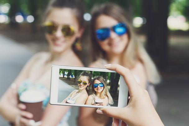 Chicas amigas tomando fotos con smartphone al aire libre
 - Foto, Imagen