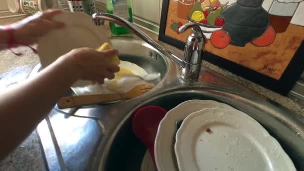 Mujer de mediana edad lava los platos en el fregadero de la cocina
 - Imágenes, Vídeo