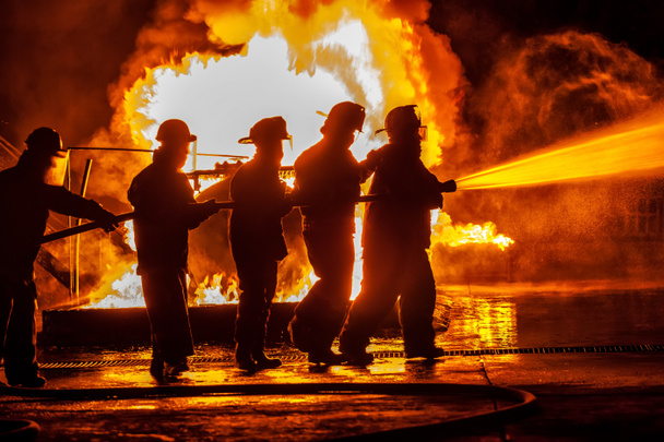 Ομάδα των πυροσβεστών που κινείται προς την φωτιά με σωλήνα - Φωτογραφία, εικόνα
