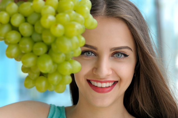 Portrait of a girl behind bunch of ripe grapes - Foto, imagen