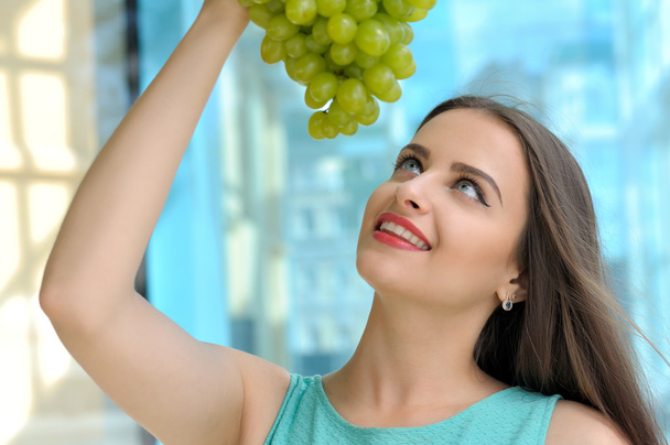 Girl holding a large bunch of grapes - Foto, imagen