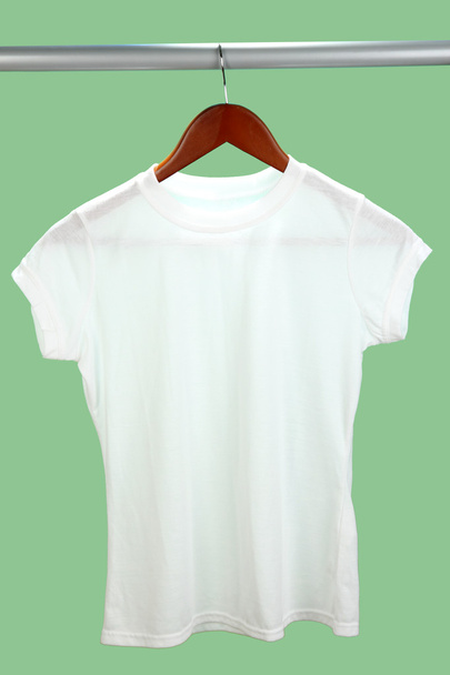 White t-shirt on hanger on green background - 写真・画像