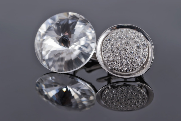 Zilveren oorbellen uit verschillende sets met steentjes op het spiegeloppervlak - Foto, afbeelding