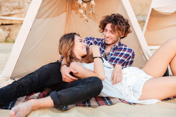 Couple lying and laughing in wigwam on the beach - Foto, Imagem