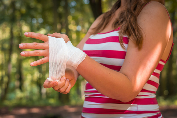 Mulher aplicando bandagem na mão após a lesão
 - Foto, Imagem