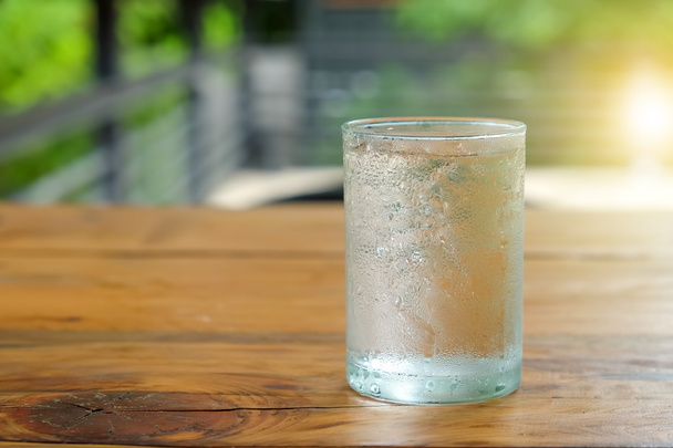 Скляна вода з краплями на скляних місцях на дерев'яному столі
. - Фото, зображення