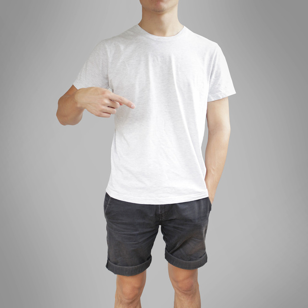 Young man with blank white shirt, front. Pointing to a t-shirt.  - Fotó, kép