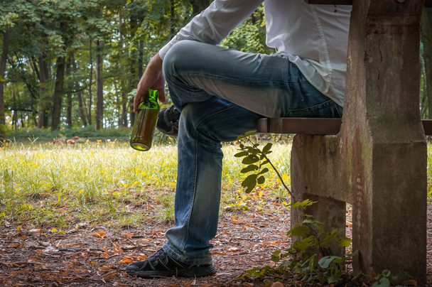 Depressieve dronken man met bierfles zittend op de Bank - Foto, afbeelding