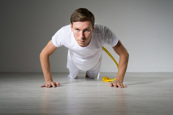Young man doing pushups on the floor. - Фото, изображение