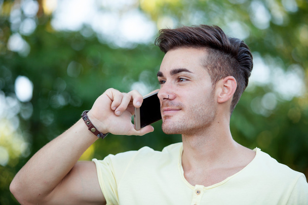 Attractive man with mobile phone in the park - Foto, imagen