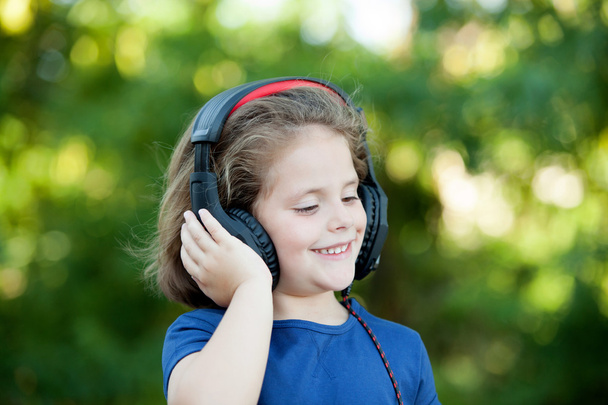 Kleines Mädchen mit Kopfhörern draußen - Foto, Bild