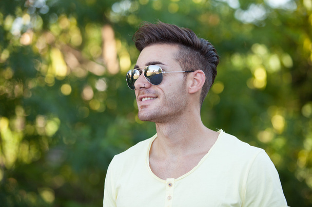 Attractive guy in the park with sunglasses  - Foto, imagen