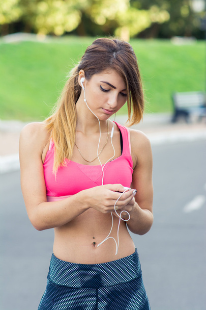 Young female runner turns on the music before the run - Photo, image