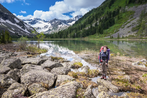 Woman is hiking on trail at the lake in mountains of Altai - Photo, Image