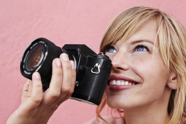 fotógrafa femenina mirando hacia arriba con la cámara en las manos
 - Foto, Imagen