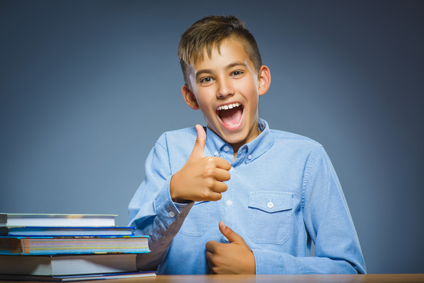 school concept. Smiling happy boy sitting at desk and show thumbs up - Foto, Imagem