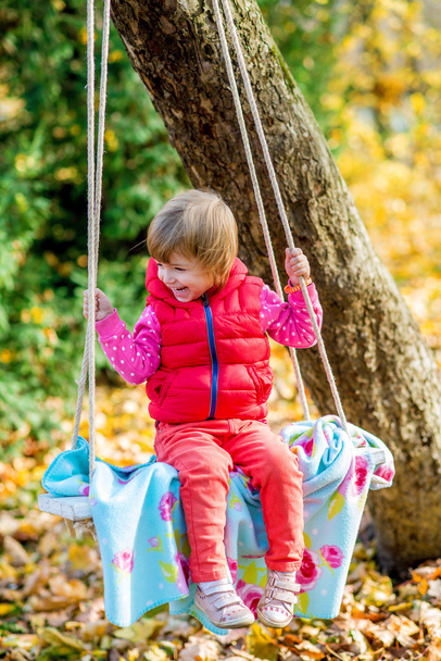 schattig meisje op een schommel op mooie herfst dag plezier - Foto, afbeelding