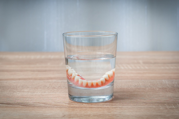 De fausses dents nagent dans un verre d'eau transparent
 - Photo, image