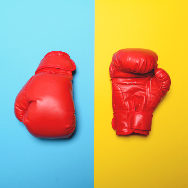 Red boxing gloves on blue and yellow background - Flat lay - Foto, imagen