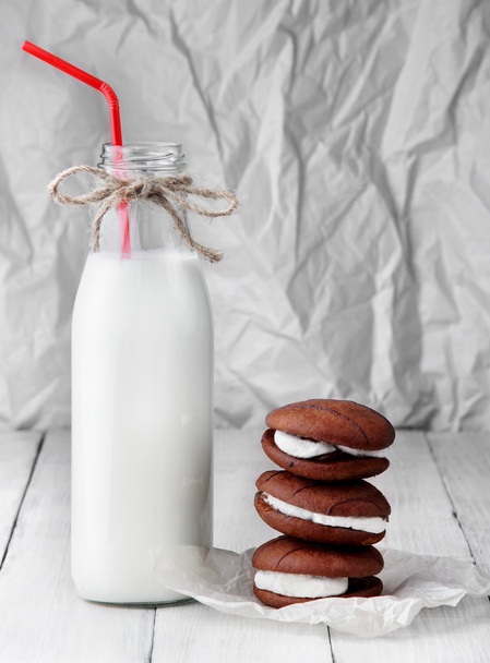 stack of sponge cookies with cream and bottle with milk with tubule. - Foto, Imagem