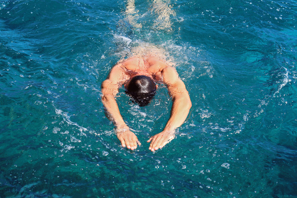 starker athletischer Mann, der Schmetterlingsstil im Meer schwimmt. Aktive Sommerferien. Sport, gesunder Lebensstil - Foto, Bild
