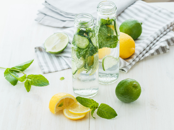 Infused water with citrus and mint in glass bottles on wooden ba - 写真・画像