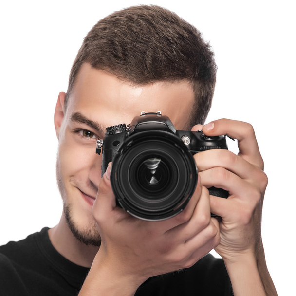 Guapo joven sosteniendo una cámara réflex digital
. - Foto, imagen