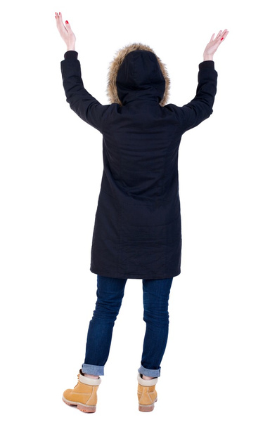 Back view of Beautiful woman in parka looking at wall and Holds - Фото, изображение