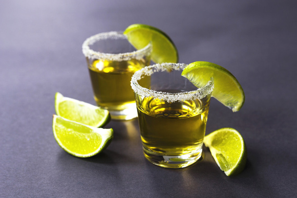 Gold tequila with lime and salt on dark table - Fotoğraf, Görsel