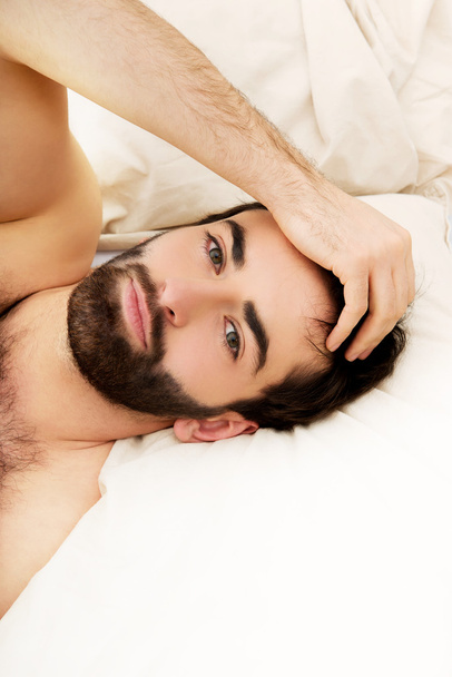 Young muscular man lying in bed. - Фото, зображення