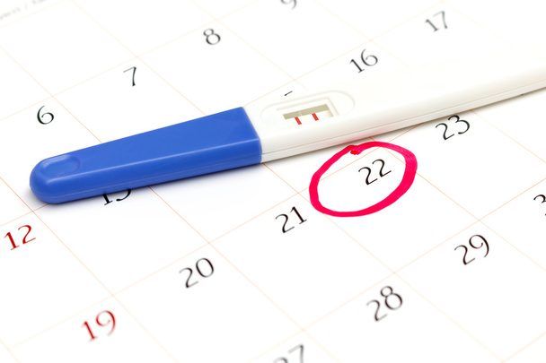 Schwangerschaftstest mit positivem Ergebnis liegt auf Kalender - Foto, Bild