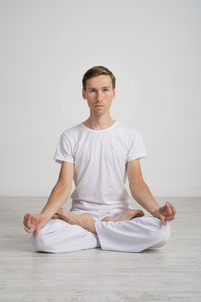 Young man meditating in Lotus position on the floor - Foto, Bild